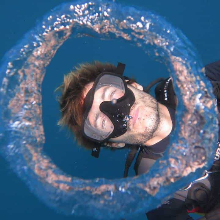 Lionel Kobi blowing a bubble ring underwater during a scuba dive.